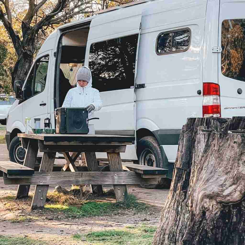 Lady Cooking on a table outside a campervan