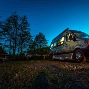 Campervan parked under tress and almost night