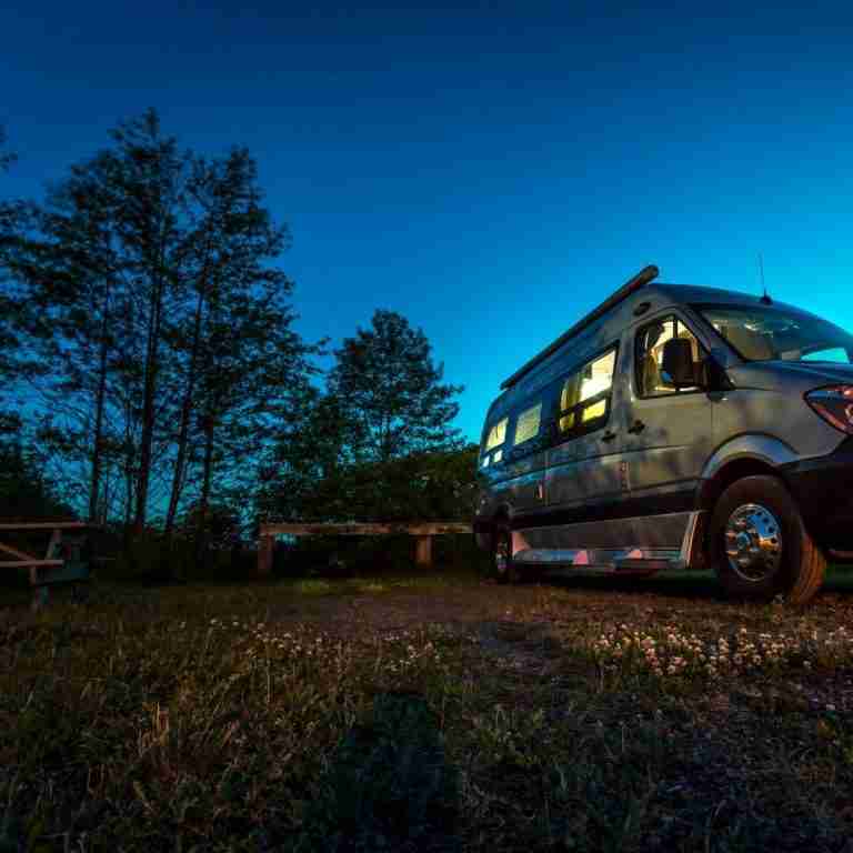 Campervan parked under tress and almost night