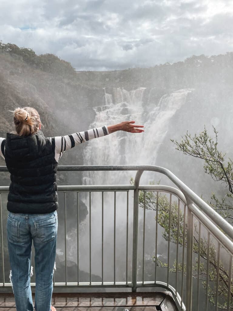 Dani with arms out looking at the waterfall 