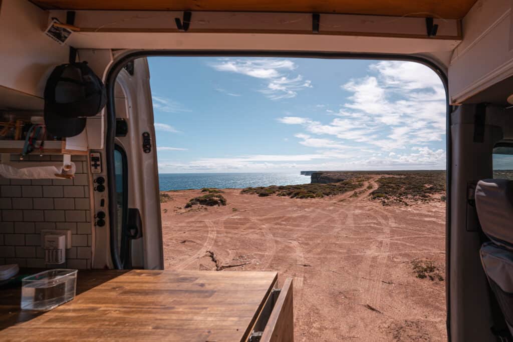 Our campervan parked next to Bunda Cliffs with the doors open. View from inside the van looking at the cliffs. 