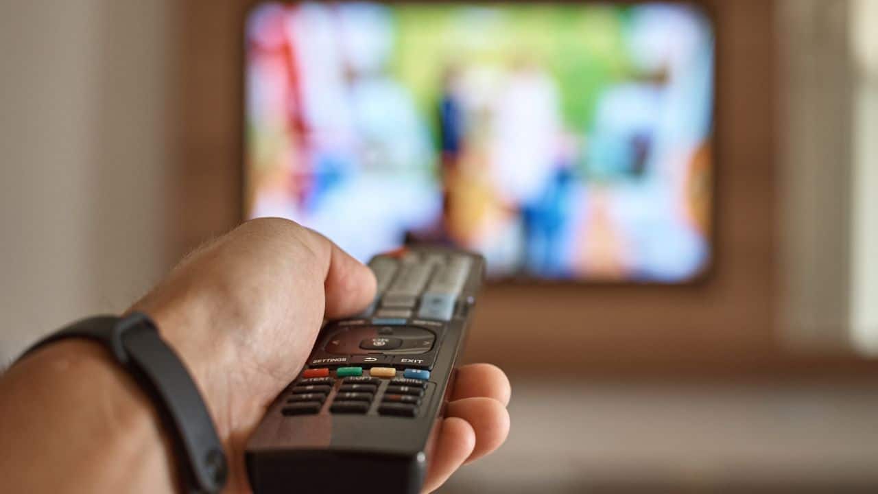 A man turning on a tv with a tv remote