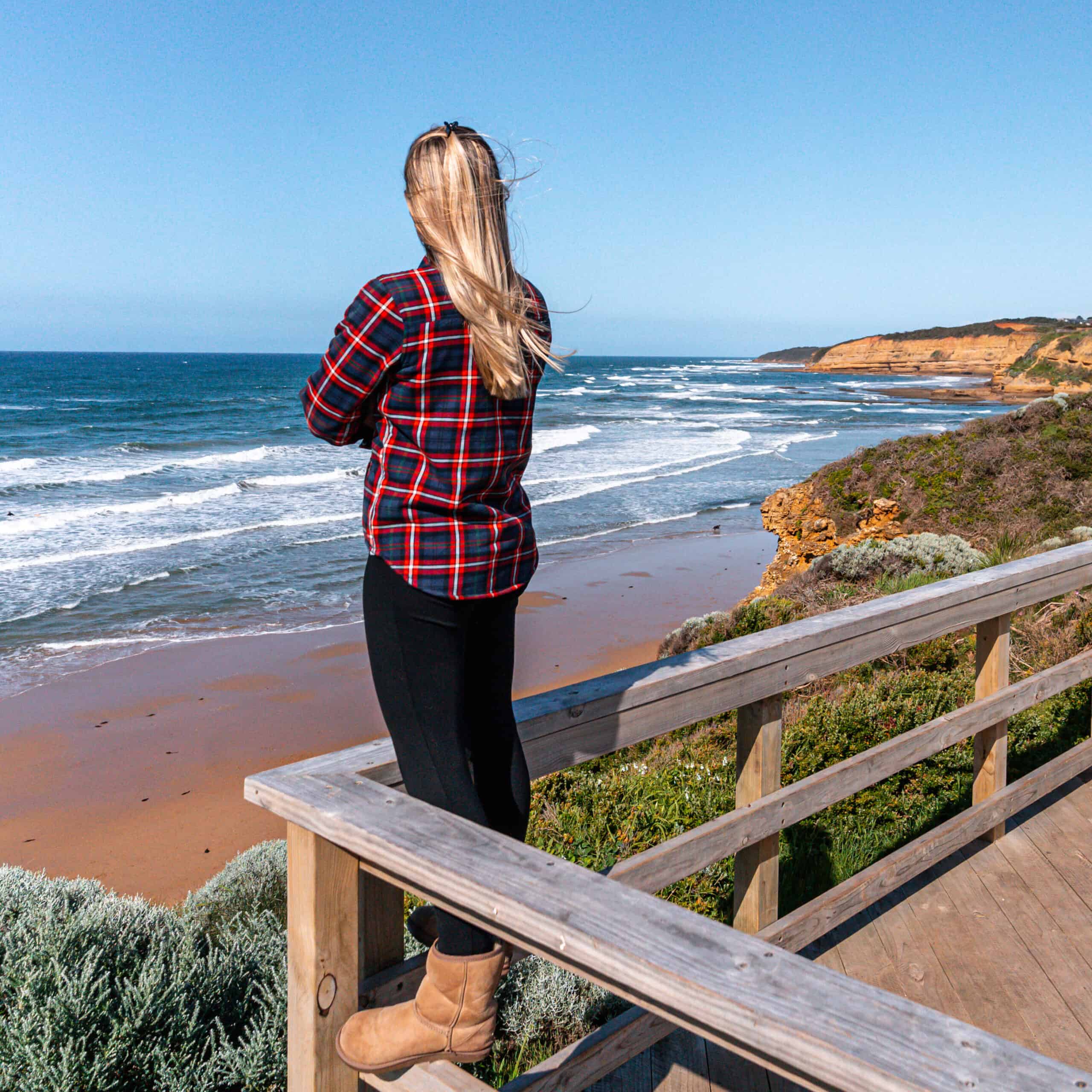 Dani standing on a wooden ledge admiring the cliffs by the beach at Jan Juc