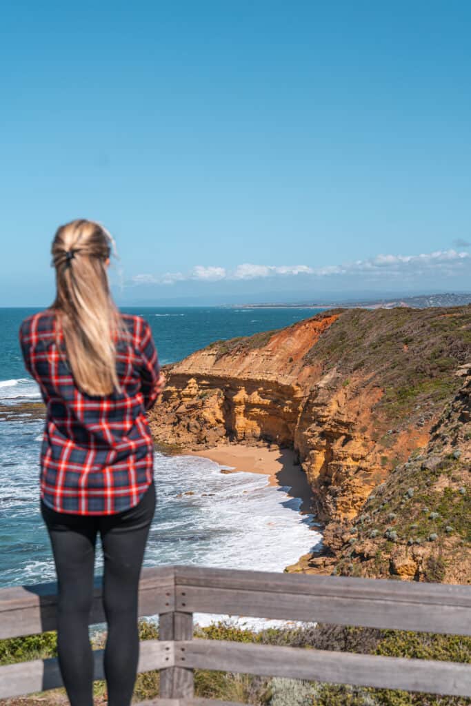 Dani standing on a ledge admiring the cliffs by the beach at Bells Beach