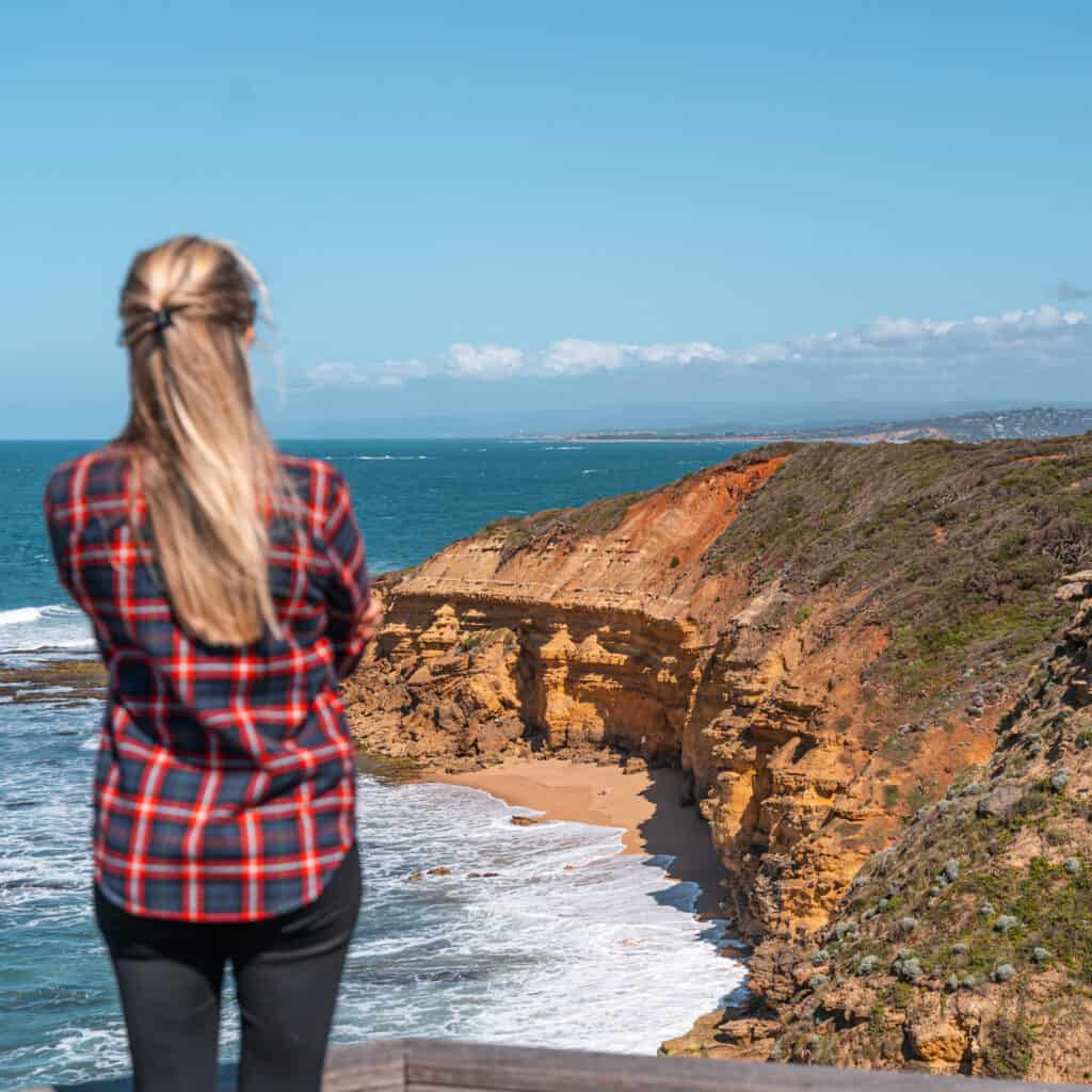 Dani is standing on a wooden platform enjoying the views of Jan Juc Beach