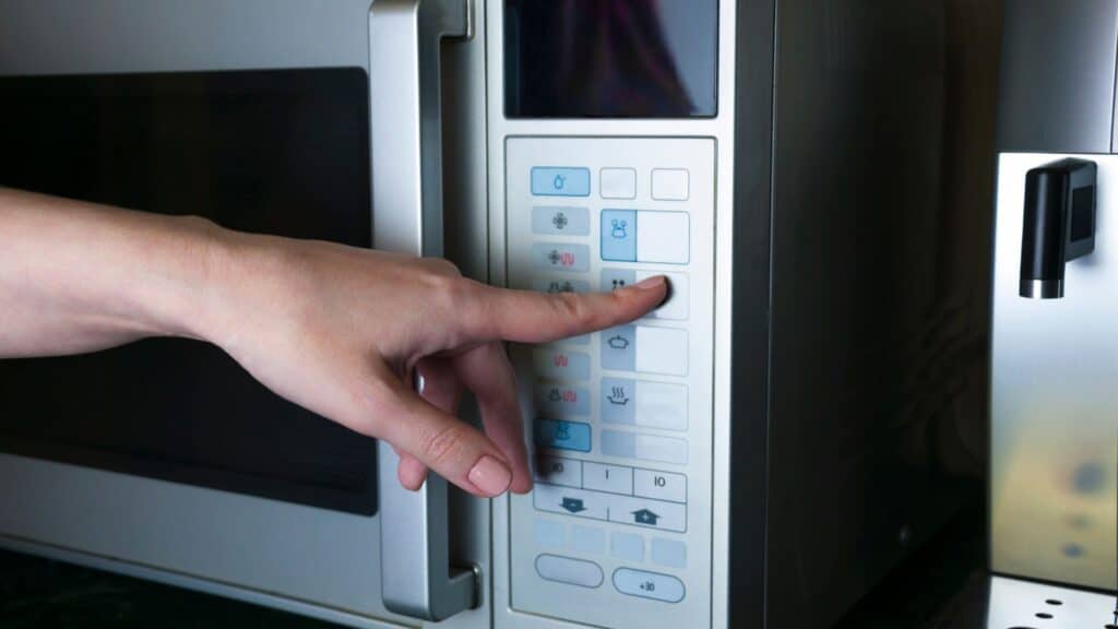 Microwave with a hand pushing a button