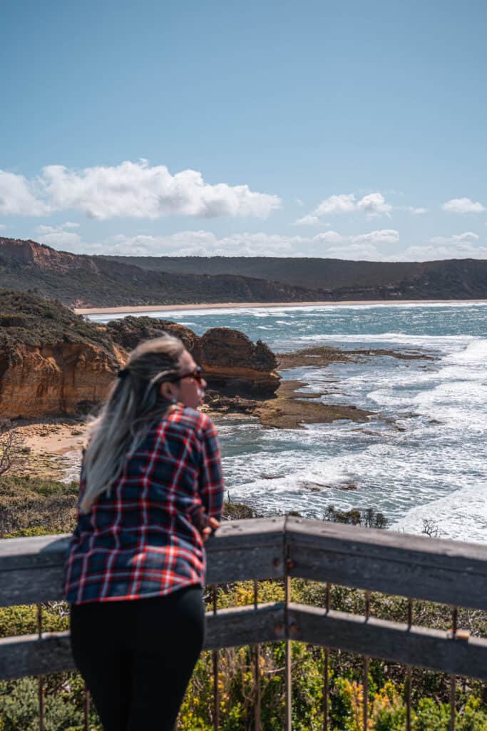 Dani leaning over a wooden platform at Point Addis Lookout enjoying the view of the cliffs in front of her