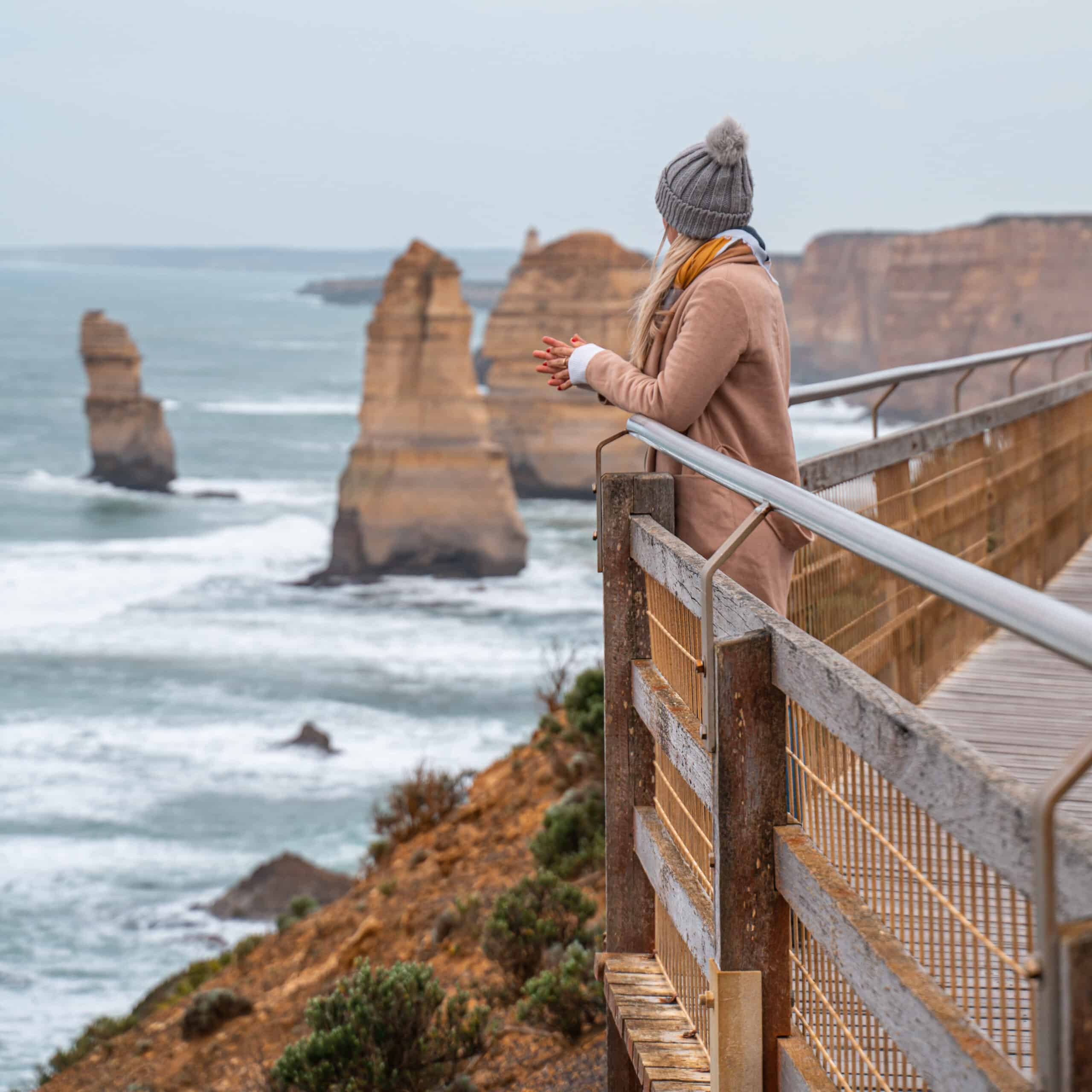 Dani standing on a wooden platform overlooking the 12 Apostles