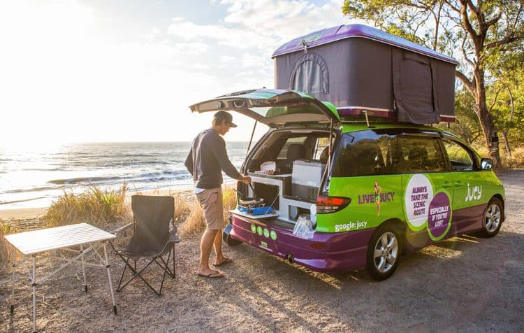 Man cooking out the back of a Jucy Rentals van