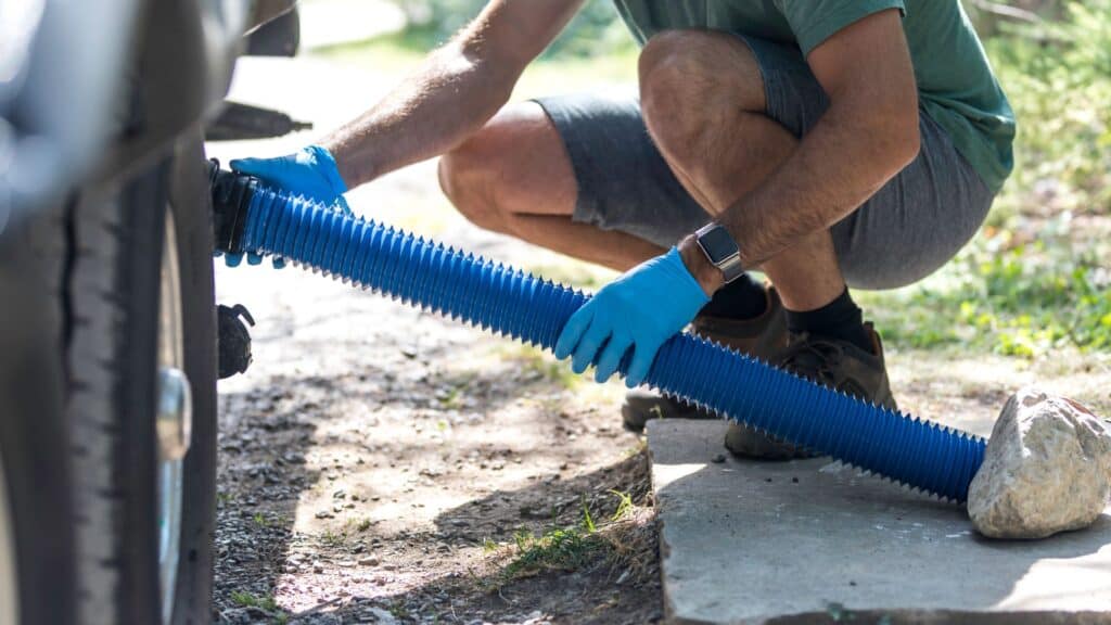 Man using a pipe to drain caravan grey waste water