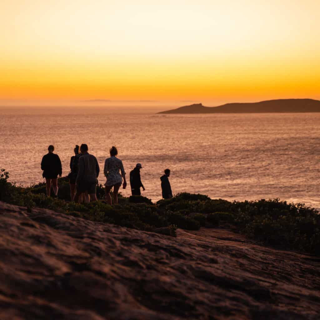 A group of people going down a mountain during sunset in Wharton Beach 