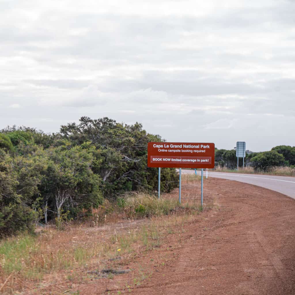 A sign on the side of the road that reads: Cape Le Grand National Park. Online campsite booking required. Book Now - limited coverage in park! 