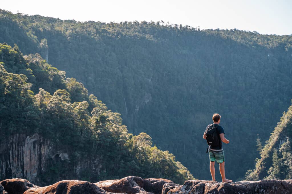 Wade standing next to the edge of a rock looking down the view