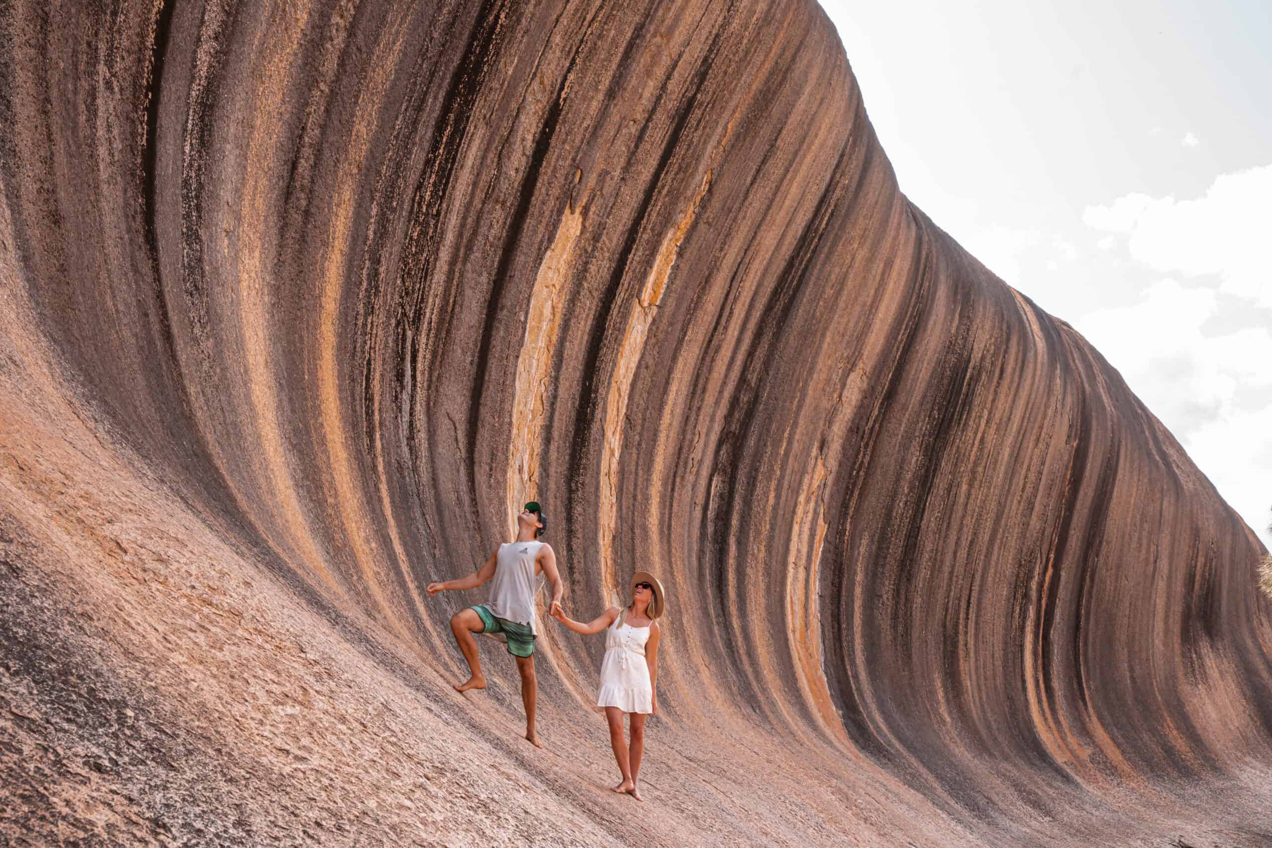 Wade and Dani holding hands and standing under the Wave Rock