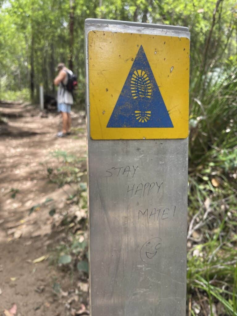 A sign in the trail to Castle Rock Granite Skywalk showing the way hikers should go. The sign also reads "Stay Happy Mate" 