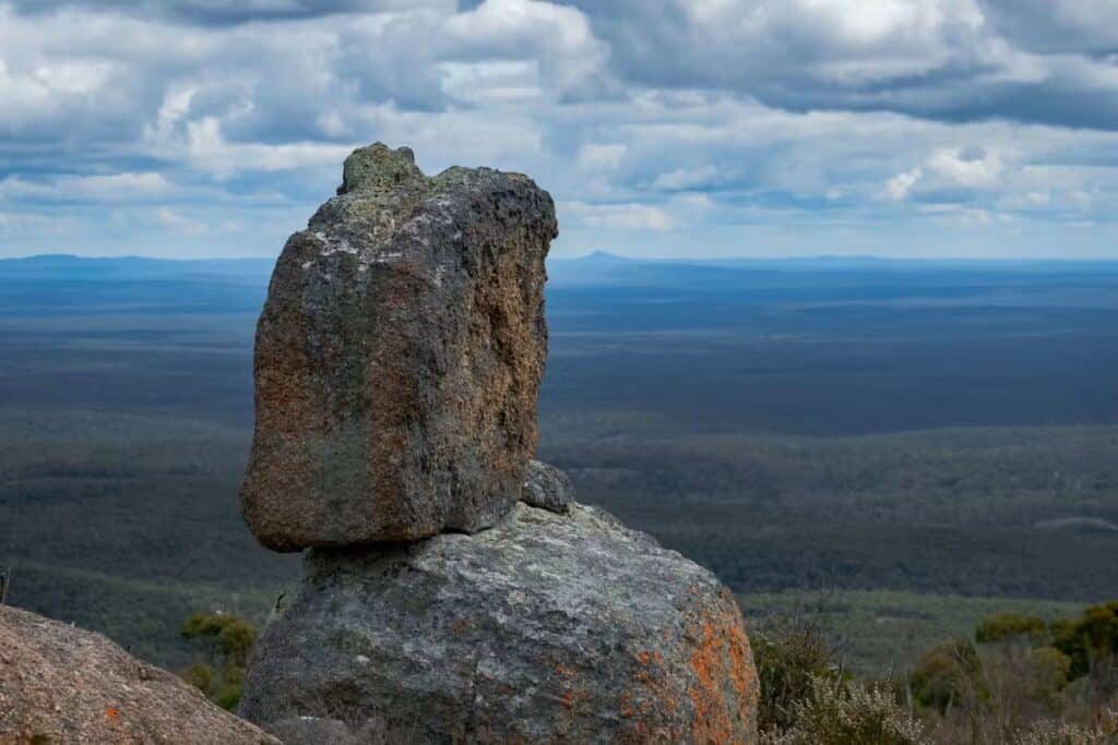 A picture of 2 rocks, one standing on top of the other at the top of a Mount.